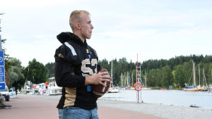 Fiskari är bland de yngsta spelarna i ligan. En man iklädd spelskjorta står med en amerikansk fotboll under armen.