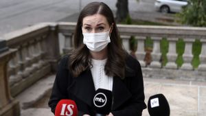Statsminister Sanna Marin (SDP) säger att situationen är upprörande. Hon bekräftar att diskussioner pågår om möjligheterna att ge de drabbade nya personbeteckningar. Kvinna i brunt hår och svart kappa och munskydd ser allvarlig ut då hon står framför tre mikrofoner på ständerhusets trappa. Kvinnan är statsminister Sanna Marin.