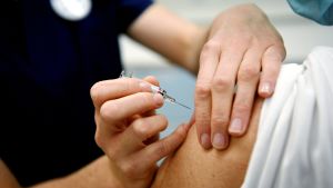 En vanlig influensasäsong vaccineras 1,5 miljoner finländare. Vårdare håller spruta intill en persons överarm.