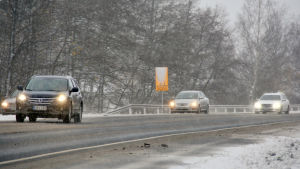 Fyra personbilar kör i trafiken. På vägen syns det slask och vid dikeskanten snö.