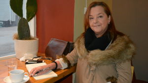 Minna Fabricius har grundat en förening som hjälper asylsökande. kvinna vid cafedisk med block och kopp