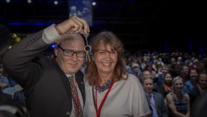 Den tidigare partisekreteraren Riikka Slunga-Poutsalo överlämnar nycklarna till partikansliet till nyvalde Simo Grönroos. Riikka Slunga-Poutsalo ger nycklarna till partikansliet till Simo Grönroos