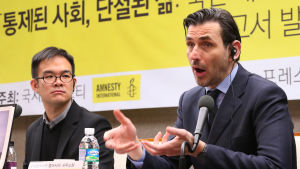 Nicholas Bequelin är regionchef Amnesty. Bequelin framför en banner med Amnestys logo och text på koreanska.