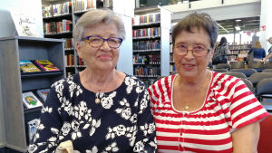 Från vänster: Marita Högström och Madeleine Michelsson. Två kvinnor sitter på stolar i ett bibliotek.