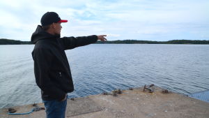 Sundvik berättar att tävlingsbanan är anpassad så att den är så publikvänlig som möjligt. En man iklädd svart jacka och keps står och pekar ut på havet