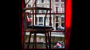 Prostitution har förekommit i Amsterdams stadskärna i århundraden. Men nu blåser det nya vindar i Amsterdam. (Bilden från museet Red Light Secrets) Tom stol vid ett fönster på museet för prostitution i De Wallen.