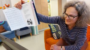Anna Brummer leder dagverksamhetens virtuella träffar på Töölön seniorikeskus, Tölö seniorcenter 2021. Sjukhusmusiker Anna Brummer leder en sångstund per distans på Tölö senioercenter under deras dagverksamhet. 2021.