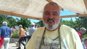 Mikael Smeds tycker att Nagu är en riktig potatisort i Finland. I Nagu odlas det nämligen mycket potatis och nypotatisen blir också tidigt färdig. mikael smeds står under ett tygtak och runtom honom passerar festivalbesökare förbi. Han ler mot kameran.