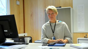 Katri Hotti undrar varför förslaget dykt upp då man inte verkar spara några pengar på det. en kvinna sitter vid sitt skrivbord i grå tröja och blont kort hår