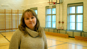 Sandra Virta som är klasslärarstuderande på Åbo Akademi i Vasa tycker att det går bra att idrotta på två språk. En ung kvinna står i en gymnastiksal.