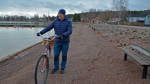 Ralf Lindén var överraskad över att vattnet hade sjunkit så snabbt. En medelålders man leder en cykel längs med stranden vid Skeppsbron i Lovisa.