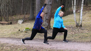 Paula Calais och Jenny Vuonoranta värmer upp för en löprunda. Två kvinnor som stretchar ute i naturen.