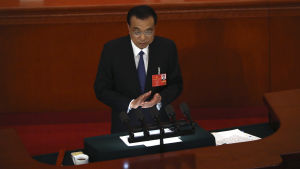 Premiärminister Li Keqiang. Kinas premiärminister Li Keqiang talar framför folkkongressen. Han står vid ett podium och klappar sina händer.