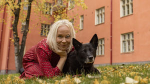 Filosofi Elise Aaltola nurmikolla koiran kanssa.
