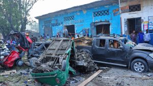 Människor står och ser på den förödelse som de två bilbomberna orsakade utanför hotellet i Mogadishu.