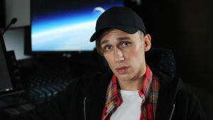Christoffer Strandberg eller Isac Elliot? Christoffer Strandberg utklädd till Isac Elliot. Han bär svart keps, rutig skjorta och svart munkjacka.