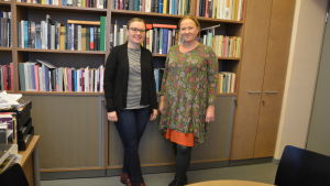 Från vänster: Maarit Leskelä-Kärki och Tiina Mahlamäki två kvinnnor står framför en bokhylla