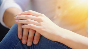 En man håller handen på en kvinnas knä.