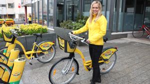 Johanna Nyberg berättar att under försöket med 100 stadscyklar i Esbo ifjol märkte de att cyklarna användes flitigt kring metrostationerna och längs havet vid rekreationsområden. Johanna Nyberg och en stadscykel.