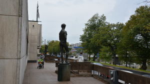 Wäinö Aaltonens museum utifrån, en staty av en man står i förgrunden, en kvinna skuffar en barnvagn i bakgrunden.