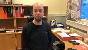 Nyvalda rektorn Johan Nilsson har arbetat som studiehandledare vid Hangö gymnasium och Hangö högstadium. En man med skägg iklädd i mörkblå tröja sitter på sitt kontor.