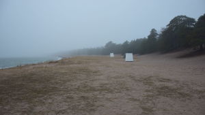 Tullstranden i väntan på badgäster och skogsmaskiner. Vem skräpar ner mer? Förhoppningsvis ingen. En öde strand med badhytter en dimmig morgon i mars.