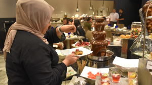 Malajerna äter stora mängder sötsaker under ramadan. Många går upp i vikt även om de fastar på dagarna. En kvinna tar chokladsås från ett buffébord.