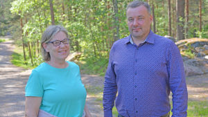Mona Bäckman och Markus Lindroos är ivriga över förnyelserna. En man och en kvinna står vid en tallskog och ler.
