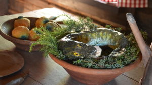Gädda och rovor var en vanlig måltid innan det fanns potatis att få i skärgården. En konstgjord gädda ligger på enrisbädd i ett fat, i bakgrunden syns en skål med rovor.