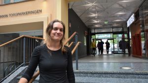 Malin Mäkinen i Vasa. En ung leende kvinna i svart tröja står vid en trappa i ett köpcenter.