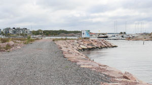 Från Drottningberg ser man bostadshusen på Fabriksudden. en grusväg vid havsstrand och småbåtshamn