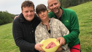 Ia Aséns får betar på olika platser i Västnyland. Bilden är tagen när Asén deltog i Svenska Yles projekt Närmat i Västnyland Michael Björklund, Ia Asén och Matias Jungar, fotograferade på en äng. De håller i en plastbunke med lammfärs.