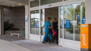 Vasa sjukvårdsdistrikt skulle i framtiden heta Österbottens välfärdsområde. Arkivbild från Vasa centralsjukhus. En sjukskötare och patient går in genom sjukhusdörrar