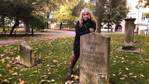 Stina Wollter står bokstavligen på de döda i Gamla Kyrkoparken i centrum av Helsingfors Stina Wollter står lutad över en gravsten i Petsparken