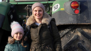 Katarina Stahl med sin dotter. Katarina Stahl med sin dotter framför en traktor.