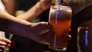 En servitör på en bar fyller ett glas med öl från en ölkran