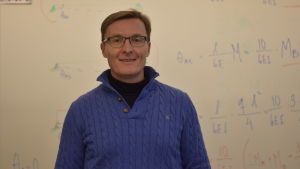 Mats Lindholm har utbildat byggmästare och ingenjörer i långt över tio år. En man med glasögon och blå tröja. Bakom en vit skoltavla med matematiska formler