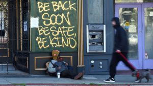 En hemlös man i San Francisco. Staden har fått beröm för sin coronahantering, men kritiker menar att man försummat de hemlösa. En bostadslös man sitter lutad mot en byggnad på en gata i San Francisco, Kalifornien den 1 april 2020.