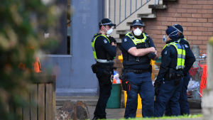 Poliser övervakar ingången till ett av de nio bostadskomplex i Melbourne som har isolerats på grund av många coronafall bland invånarna. Poliser övervakar ingången till ett bostadskomplex som har isolerats på grund av många coronafall bland invånarna.