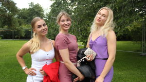 Tre unga kvinnor på festival ler. 