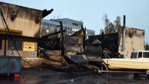 Vissa delar av industrifastigheten är helt förstörda. Nedbrunnet hus med plåtväggar som står.