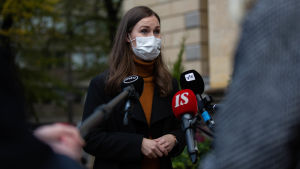 Marin säger att åtgärderna måste vara rätt avvägda och fungera. Beredningsarbetet pågår, men mera än så ville Marin inte kommentera eventuella begränsningar av rörelsefriheten. Sanna Marin framför mikrofoner på Ständerhusets trappa