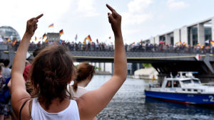 En motdemonstrant visar långfingret åt AfD-demosntrationen i Berlin i maj 2018.