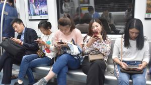 I Hongkongs grannstad Shenzhen kretsar allt fler människors liv helt kring deras smarttelefoner. Mer än 600 miljoner kineser äger en sådan. kinesiska personer sitter på metro och ser på sina mobiltelefoner.