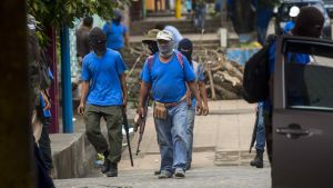   Armed supporters of President Ortega patrolled the streets in Masaya , after storming the area and repelling protesting residents in bloody battles. 