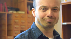 Kristoffer Holmberg ansvarar för musiklinjerna på Lärkkulla. närbild man i bibliotek