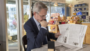 Pekka Haavisto studerar innehållet i lokaltidningen för Munksnäs. Pekka Haavisto Munkkivuoren ostarilla 5.3.2019