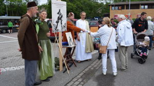 Några utklädda skådespelare från teatergruppen Fjerden delar ut information om En midsommarnattsdröm på Dalsbruks torg.