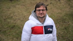 Timo Eklund påpekar att den finländska exporten ökar trots att den sjunker i andra länder. En yngre man i vinterjacka tittar snett uppåt mot kameran med en gräsmatta i bakgrunden.