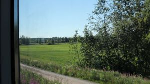 I framtiden ska man kunna pendla mellan Borgå och Helsingfors på 30 minuter. Landskapsutsikt en sommardag genom ett tågfönster.